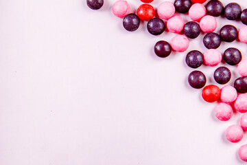 Light pink background with round pink and purple candys on the right side. Top view with copy space