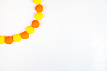 White background with round candys in the left corner. Border of sweet yellow and orange candys