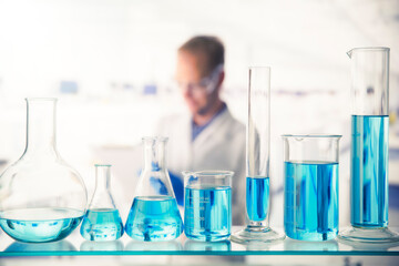 Close up of various solutions in beakers on shelf in lab