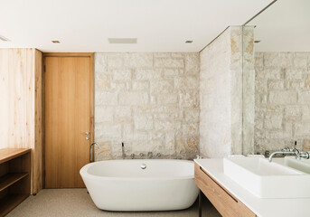 Stone walls behind soaking tub in modern bathroom