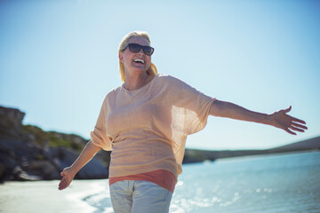 Older woman smiling in sun on beach 