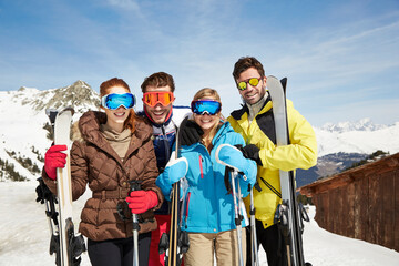 Friends on mountain top holding skis together 