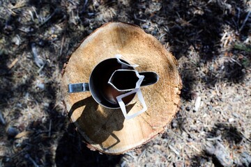 Coffee on a tree trunk. Hand-brewed dripped black coffee on a tree trunk with annual ring in the wood. Beautiful canopy shadow is around.