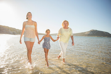 Three generations of women walking in waves