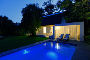 Modern house overlooking illuminated swimming pool at night