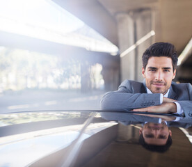 Businessman resting on car in parking garage