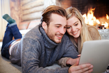 Couple using digital tablet by fireplace together