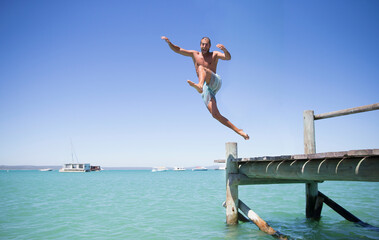 Couple jumping off wooden dock into water
