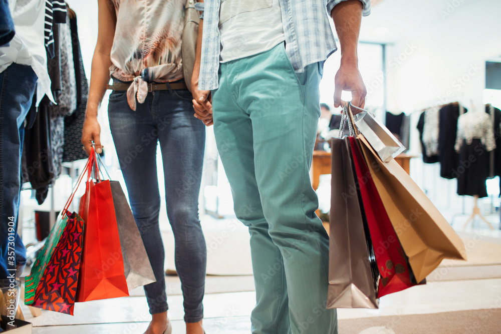 Poster Couple carrying shopping bags in clothing store