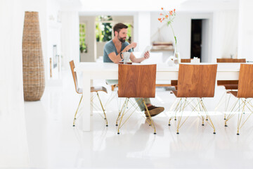 Man using digital tablet at breakfast table in modern dining room
