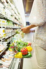 Woman carrying full shopping basket in grocery store