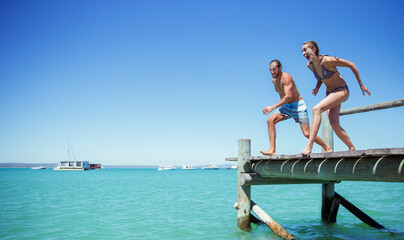 Couple jumping off wooden dock together