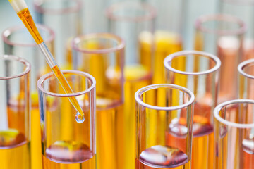 Close up of pipette dropping solution into test tube in rack in lab