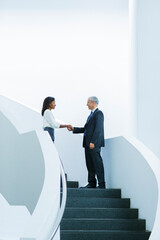 Business people shaking hands on stairs of office building