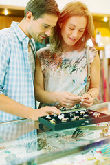 Fototapeta premium Couple examining jewelry together in store