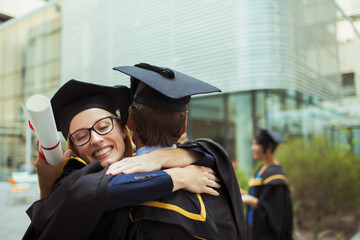 Students in cap and gown hugging