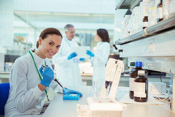 Scientist pipetting samples into tray in laboratory