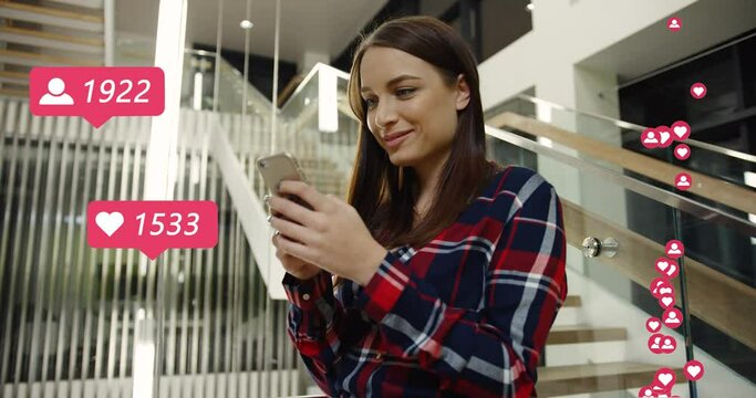 Young Caucasian pretty woman standing indoor in business center and posting in social media. Female blogger getting reactions, likes and followers for post. Girl putting hearts online on smartphone.