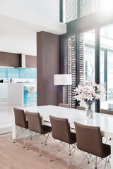 View of modern dining room with white lilies in vase on table
