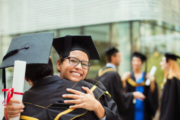 Students in cap and gown hugging