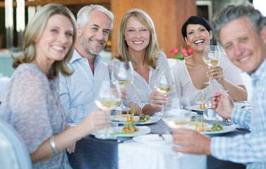 Portrait of smiling people toasting with white wine in restaurant