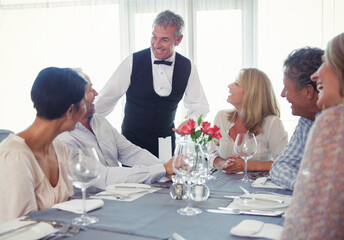People sitting at restaurant table and talking to waiter