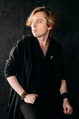 Portrait of a handsome young man with blond hair on black background, dramatic shot, posing