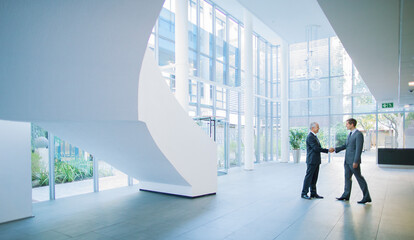 Businessmen shaking hands in office building