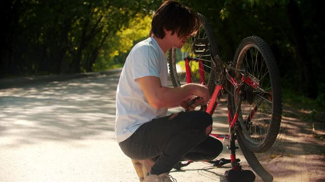 Young man fixing his bike in the park
