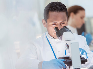 Scientist examining sample under microscope in laboratory