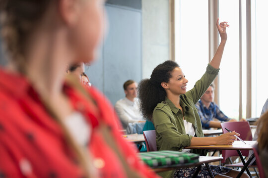 Female student raising hduring lecture with other students 