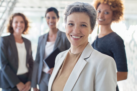 Portrait of smiling mature businesswoman with office team 