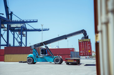 Fototapeta premium Crane lifting cargo container onto truck