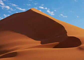 Plakat View of sand dunes in desert with blue sky and clouds in background