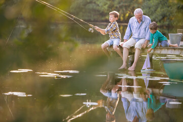 Grandfather grandsons fishing playing with toy sailboat at lake - Powered by Adobe