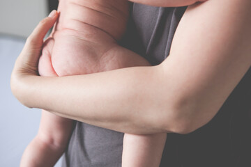 View of mother's hands holding little naked baby