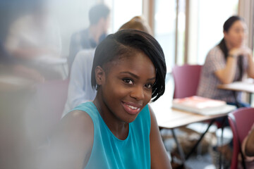 Fototapeta premium Smiling female student during lecture looking at camera other students 