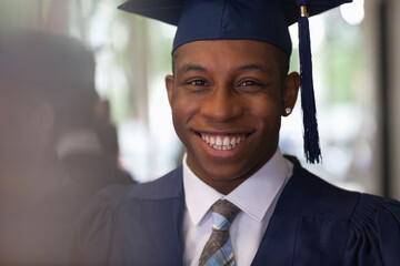 Male student wearing graduation clothes and smiling at camera