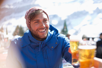 Smiling man in warm clothing drinking beer outdoors