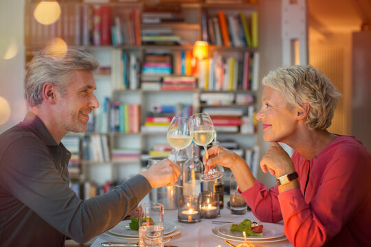 Older Couple Toasting Each Other At Romantic Dinner