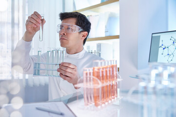Man working in laboratory holding vial