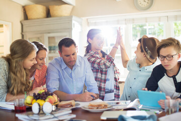 Obraz premium Teenagers with mid adult man sitting at table in dining room