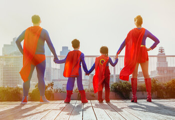 Superhero family standing on city rooftop