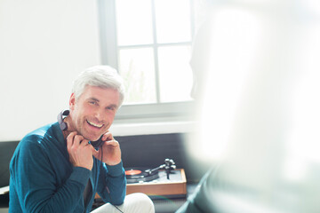 Older man listening to turntable with headphones © Tom Merton/KOTO