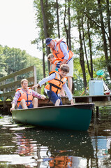 Obraz premium Boy, father and grandfather climbing into canoe
