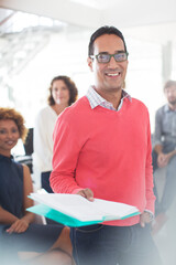 Fototapeta premium Portrait smiling businessman wearing glasses pink sweatshirt holding documents, office team 
