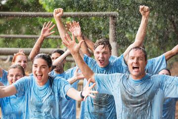 Enthusiastic team cheering in rain on boot camp obstacle course