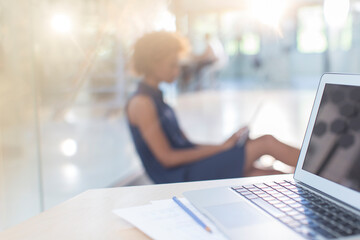 Obraz na płótnie Canvas Open laptop on desk, woman in background