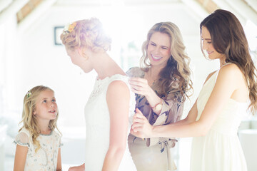 Matron of honor bridesmaid helping bride dressing in domestic room