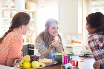 Three teenage girls talking at table in dining room